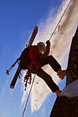 Man rappelling during small avalanche with skis on his back on Donner Summit, California. USA