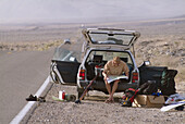 A man sitting on tailgate of car in the desert