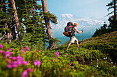 A man hiking through flowers in the Tatoosh range near Mount Rainier, WA.