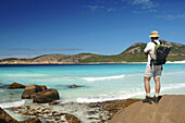 Walker on the Coastal Track pauses to take in stunning colours of Thistle Bay, Cape Le Grand National Park, near Esperance, Western Australia.