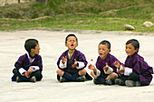 Young Bhutanese schoolboys wearing ghos (native costume) and singing, Bumthang Valley, Bhutan