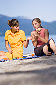 Two young women, girls, having a picnic on the lake shore, Lake Walchensee, Upper Bavaria, Bavaria, Germany