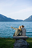 Zwei junge Frauen sitzen am Ufer vom Walchensee, Bayern, Deutschland