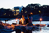 Two young women sitting at river Isar in the evening, Munich, Bavaria, Germany