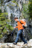 Man hiking in the Gorge, Crossing a stream, Partnachklamm, Garmisch-Partenkirchen, Bavaria, Germany