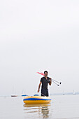 Young man pulling rubber dingy to shore, Lake Ammersee, Bavaria, Germany