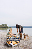 Young couple inflating a dinghy, lake Ammersee, Bavaria, Germany