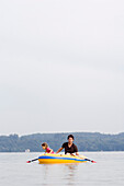 Father and daughter (4-5 years) in a rubber dingy on Lake Ammersee, Bavaria, Germany