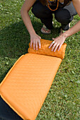 Young woman rolling up a sleeping pad