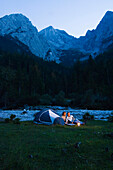 Young couple sitting near a tent, Lenggries, Upper Bavaria, Bavaria, Germany