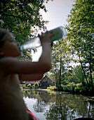 Girl drinking water during a canoe tour, farm house in Lehde, Lehder Fließ, stream, Upper Spreewald, biosphere reservat, Spreewald, Brandenburg, Germany