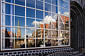 Reflection of St. John's Church and gabled houses in glass front, Luneburg, Lower Saxony, Germany