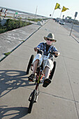 A boy rides a big tricycle on the sea wall at Galveston Texas. USA.