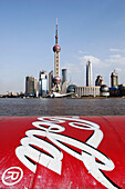 Coca Cola advertizing on the Bund with the Oriental Pearl TV tower and the skyline of Pudong business district in the background, Shanghai, China