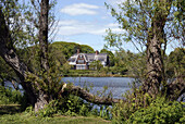 Mansion seen through trees and across water, Southampton. New York, USA