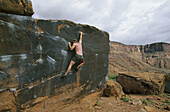 Male climber bouldering at Big Bend area near Moab, Utah, USA