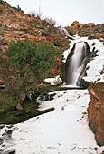 Snow and ice surrounds Faux Falls on a cold winter day, Moab, Utah, USA.