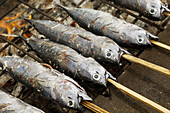 Skewered mackerel grilling on barbecue. Indonesia