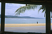 Window looking to the beach from a cabin in Monogaga river beach. Fisherman on the shore. Ivory Coast.