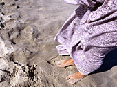 Brighten Beach, NJ, USA. A womans feet on the beach wrapped in a puple sarong.