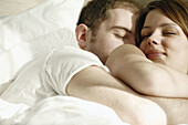 Young couple in bed cuddling together