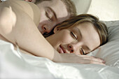 Young couple in bed sleeping and cuddling together