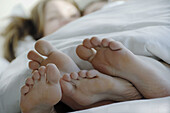 Young couples laying together in bed with feet in foreground