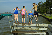 Two girls and two boys jumping into the Albemarle Sound from the dock