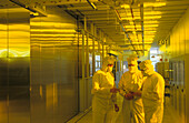Europe, Germany, Saxony, Dresden, Infineon Technologies, three co-Workers in protective clothing talking in the cleanroom class 1
