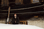 Man with closed eyes sitting outside a chalet, Hirschegg, Vorarlberg, Austria