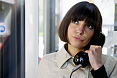 Junge Frau telefoniert in einer Telefonzelle, Düsseldorf, Nordrhein-Westfalen, Deutschland
