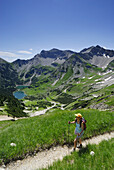 Woman hiking above lakes Soiernseen, Soiernspitze in background, Karwendel range, Bavaria, Germany