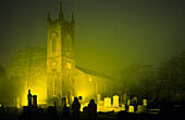 Die Kirche St. John the Baptist mit Friedhof im Nebel bei Nacht, Bushmills, County Antrim, Irland, Europa