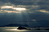 Sunbeams shining through a dark cloud cover over Blasket Island, County Kerry, Ireland, Europe