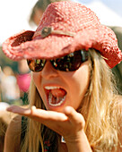 Young woman eating living tree maggot, Hokitika Wildfoods festival, Hokitika, South Island, New Zealand