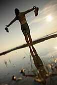 Joggerin steht barfuß am Starnberger See, Ambach, Bayern, Deutschland