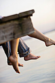 Couple sitting on a jetty, Ambach, Lake Starnberg, Bavaria, Germany