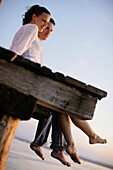 Couple sitting on a jetty, Ambach, Lake Starnberg, Bavaria, Germany