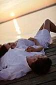 Couple lying on a jetty, Ambach, Lake Starnberg, Bavaria, Germany