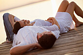 Couple lying on a jetty, Ambach, Lake Starnberg, Bavaria, Germany