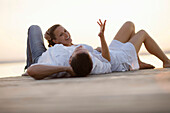 Couple lying on a jetty, Ambach, Lake Starnberg, Bavaria, Germany