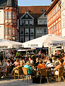 Menschen sitzen unter Sonenschirmen im Strassencafe in der Altstadt, Coburg, Franken, Bayern, Deutschland