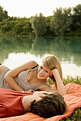 Junges Paar liegt auf einer Decke am Seeufer, Freising, Bayern, Deutschland