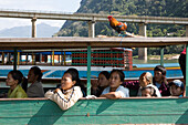 Menschen und ein Hahn in einem Boot auf dem Fluss Nam Ou, Provinz Luang Prabang, Laos