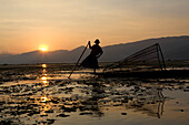 Intha fisherman on his fishing boat on Inle Lake at sunset, Shan State, Myanmar, Burma