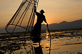 Intha fisherman on his fishing boat on Inle Lake at sunset, Shan State, Myanmar, Burma