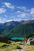 young woman descending from hut Similaunhütte down towards reservoir Vernagtsee, Ötztal range, South Tyrol, Italy