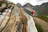 marble rock beside trail with young woman, valley Pfossental, Texelgruppe range, Ötztal range, South Tyrol, Italy