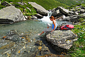 young woman bathing feet in stream, valley Lazinstal, Texelgruppe range, Ötztal range, South Tyrol, Italy