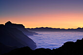 dawn above fog bank in valley Gschnitztal, Kirchdachspitze in background, Bremer Huette, Stubaier Alpen range, Stubai, Tyrol, Austria
